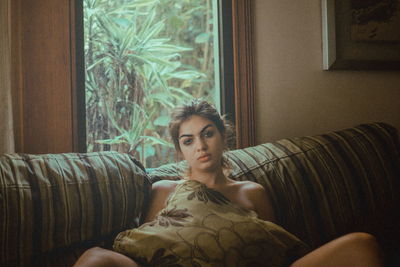 Portrait of young woman sitting on sofa at home