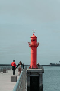 Couple walking on pier against sky