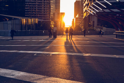 People walking on city street at sunset