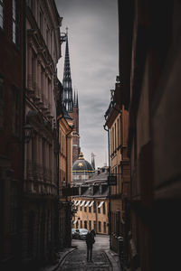 Rear view of man walking on street amidst buildings in city