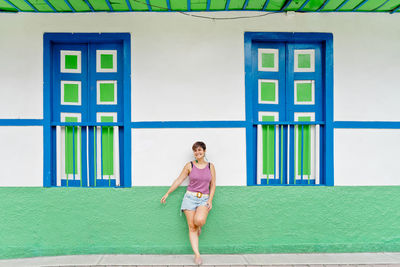 Full length of young woman standing against wall