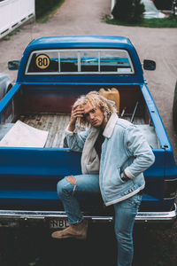 Full length of woman sitting on car