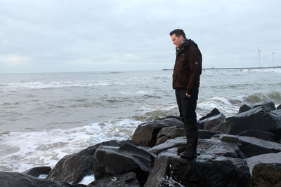 Full length of man standing on rock by sea