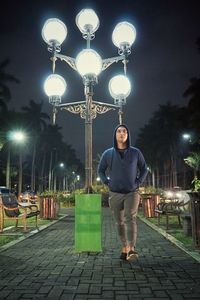 Full length portrait of man standing on street at night