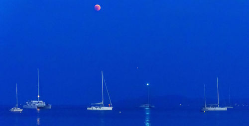 Sailboats in sea against blue sky