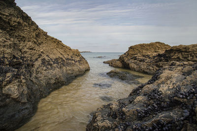 Rock formation in sea against sky