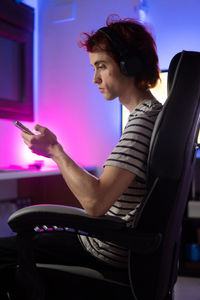 Side view of man using mobile phone while sitting on table