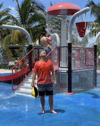 Rear view of man and woman standing at swimming pool