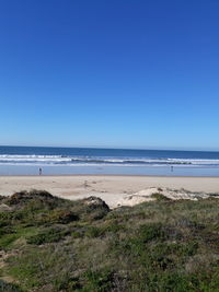 Scenic view of beach against clear blue sky