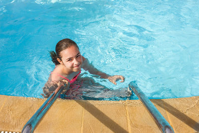 High angle portrait of smiling woman swimming in pool