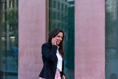 Portrait of smiling woman standing against building