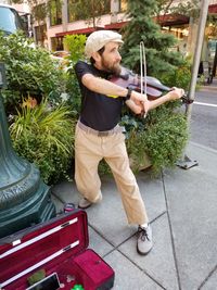 Full length of man playing violin while standing on footpath