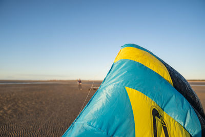 Close-up of yellow umbrella on beach against clear sky