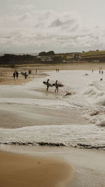 People enjoying on beach against sky