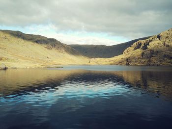 Scenic view of lake and mountains against cloudy sky