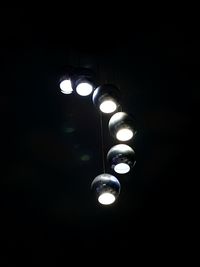 Low angle view of illuminated light bulb against black background