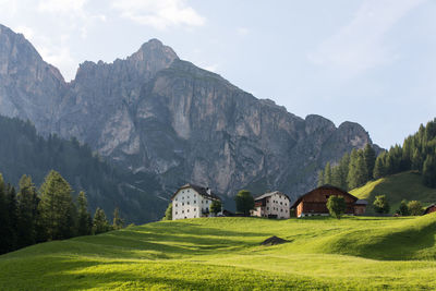 Houses on field by mountains against sky