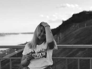 Young woman with hand in hair against hill