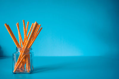 Close-up of vase on table against blue background