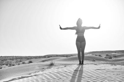 Woman standing on sand at beach against clear sky