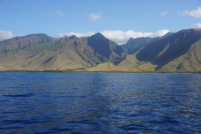 Scenic view of sea by mountains against sky