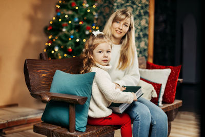 Portrait of young woman using phone while sitting on sofa at home