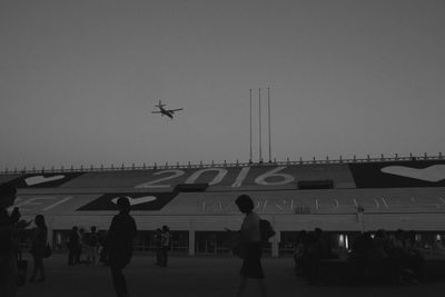 Airplane flying over airport runway against sky