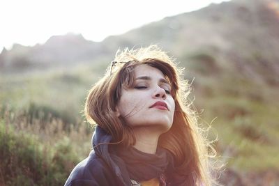 Close-up of woman with closed eyes against mountains