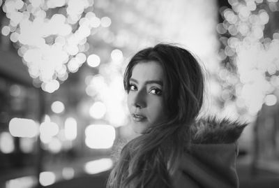 Close-up portrait of smiling young woman against illuminated tree