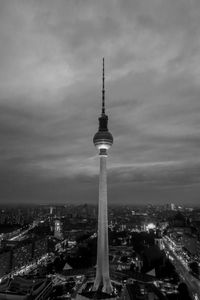 Communications tower in city against sky