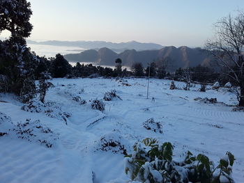 Scenic view of snow covered field against sky