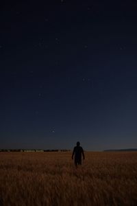 Rear view of man on field against clear blue sky