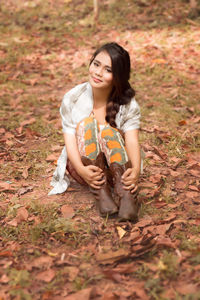 Portrait of young woman sitting on autumn leaves