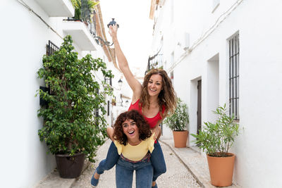 Portrait of smiling young woman standing by potted plants
