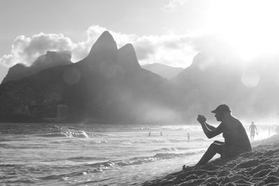 Man photographing at sea against sky