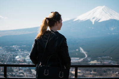 Rear view of man standing on snowcapped mountain