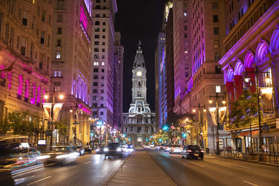 Illuminated city street amidst buildings at night