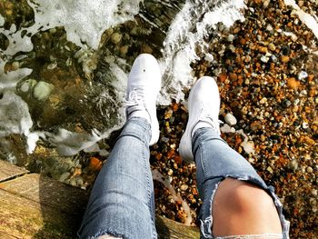 Low section of person dangling legs over lake