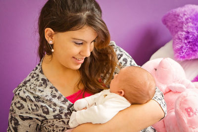 Smiling woman holding baby girl at home