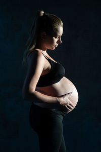 Side view of woman standing against black background