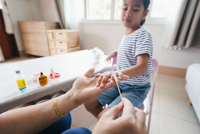 Parent helping her child perform first aid finger injury after she has been an accident.