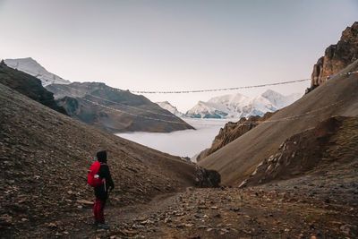 Rear view of man standing on mountain against sky