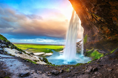 Scenic view of waterfall against sky during sunset