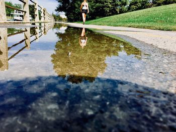 Woman walking against puddle on footpath