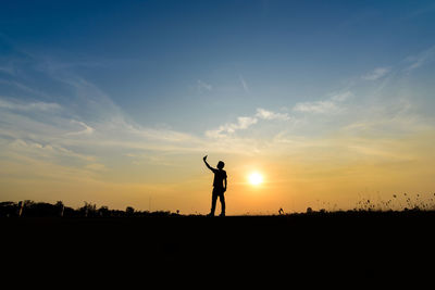 Silhouette of man standing against sky during sunset