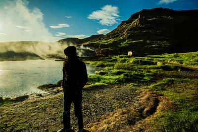 Rear view of woman standing on mountain against sky