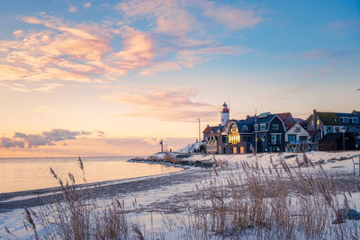 Building by sea against sky during sunset