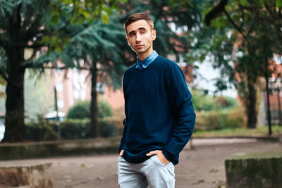 Portrait of young man standing against trees