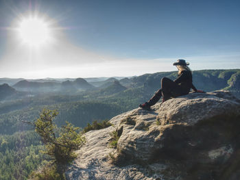 Cow woman hiker with hat and glassess enjoying amazing valley landscapes view on a top of mountain.