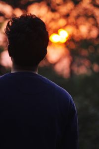 Rear view of man standing against orange sky